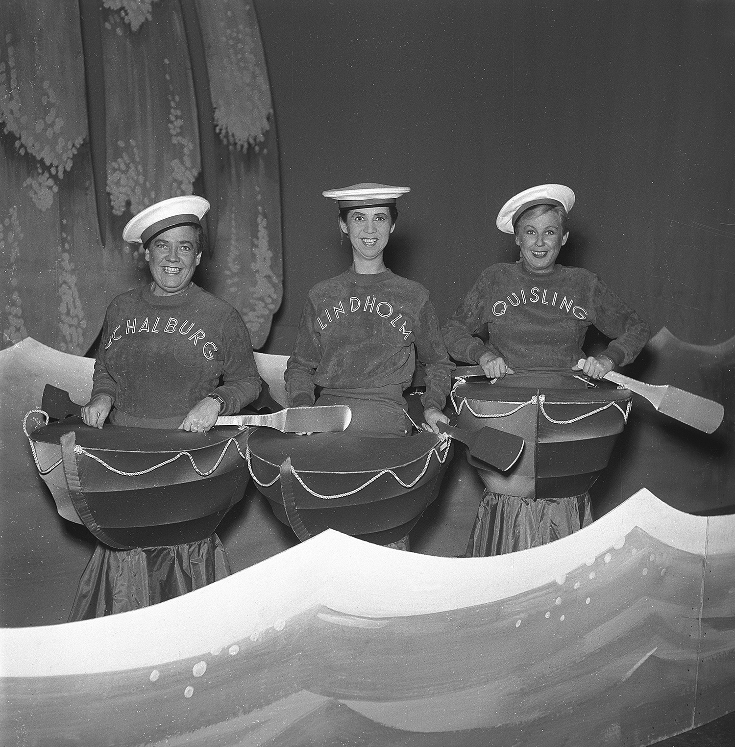 Tre kvinnor på scenen i sjömansdräkter och med varsin liten båt som rekvisita