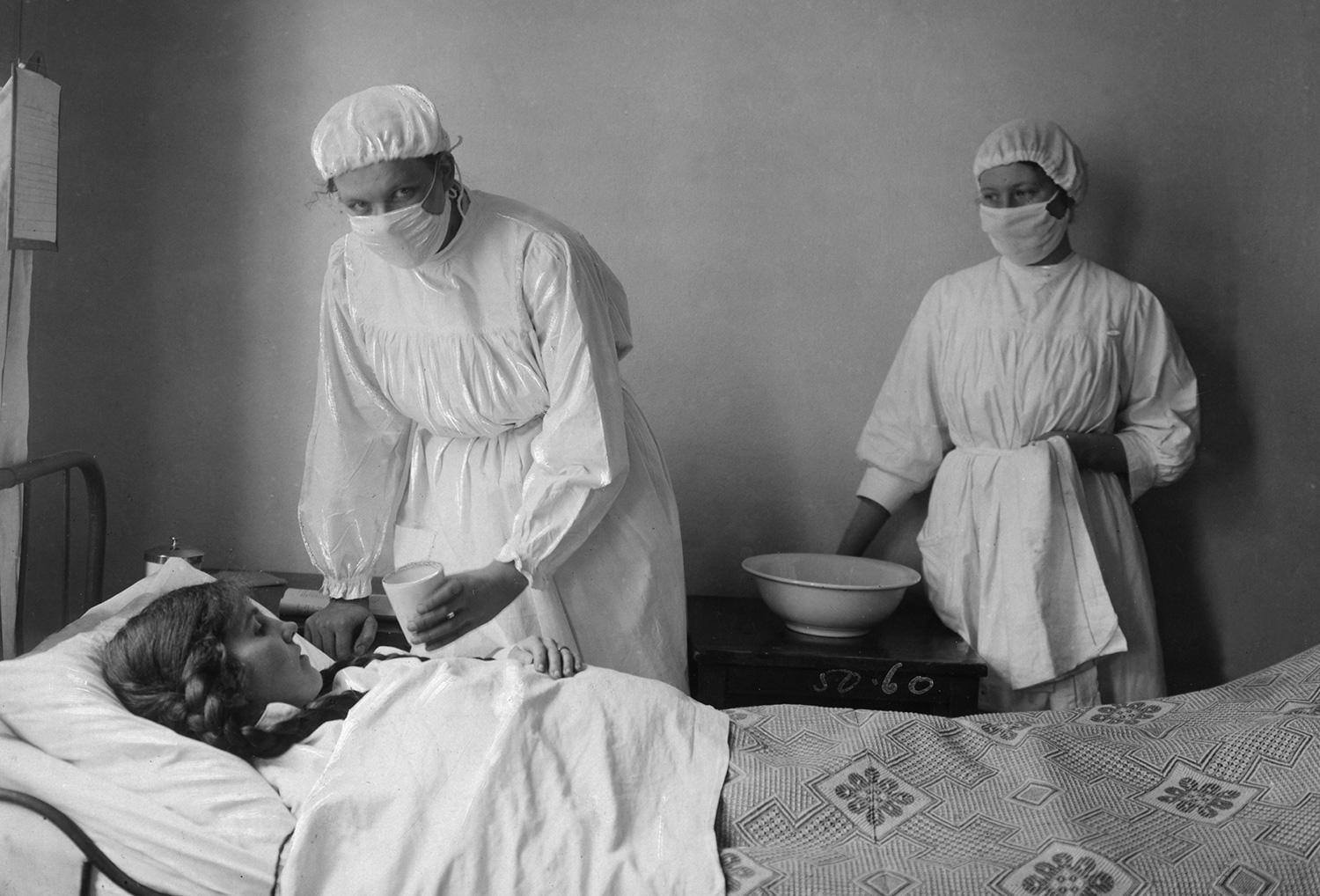 En kvinnlig patient får vård av vårdpersonal i vita kläder och munskydd