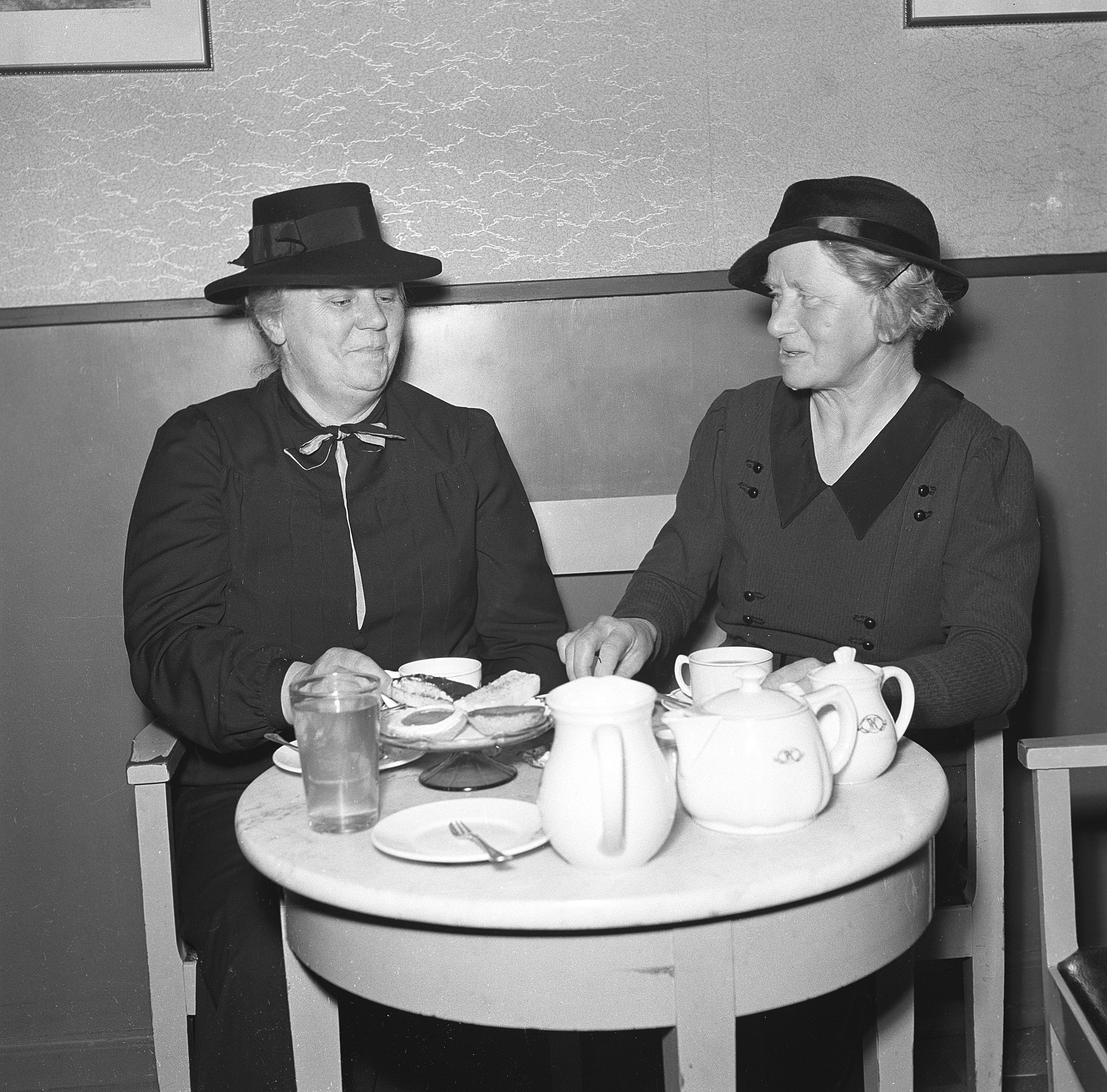 Två äldre damer dricker kaffe och fikar.